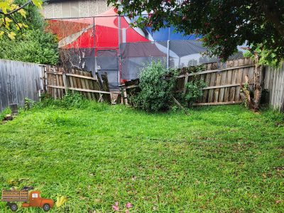 Backyard scene with an old wooden fence, chain-link fence, red tent behind, and overgrown grass and bushes; a cartoon orange truck graphic sits at the bottom-left corner.